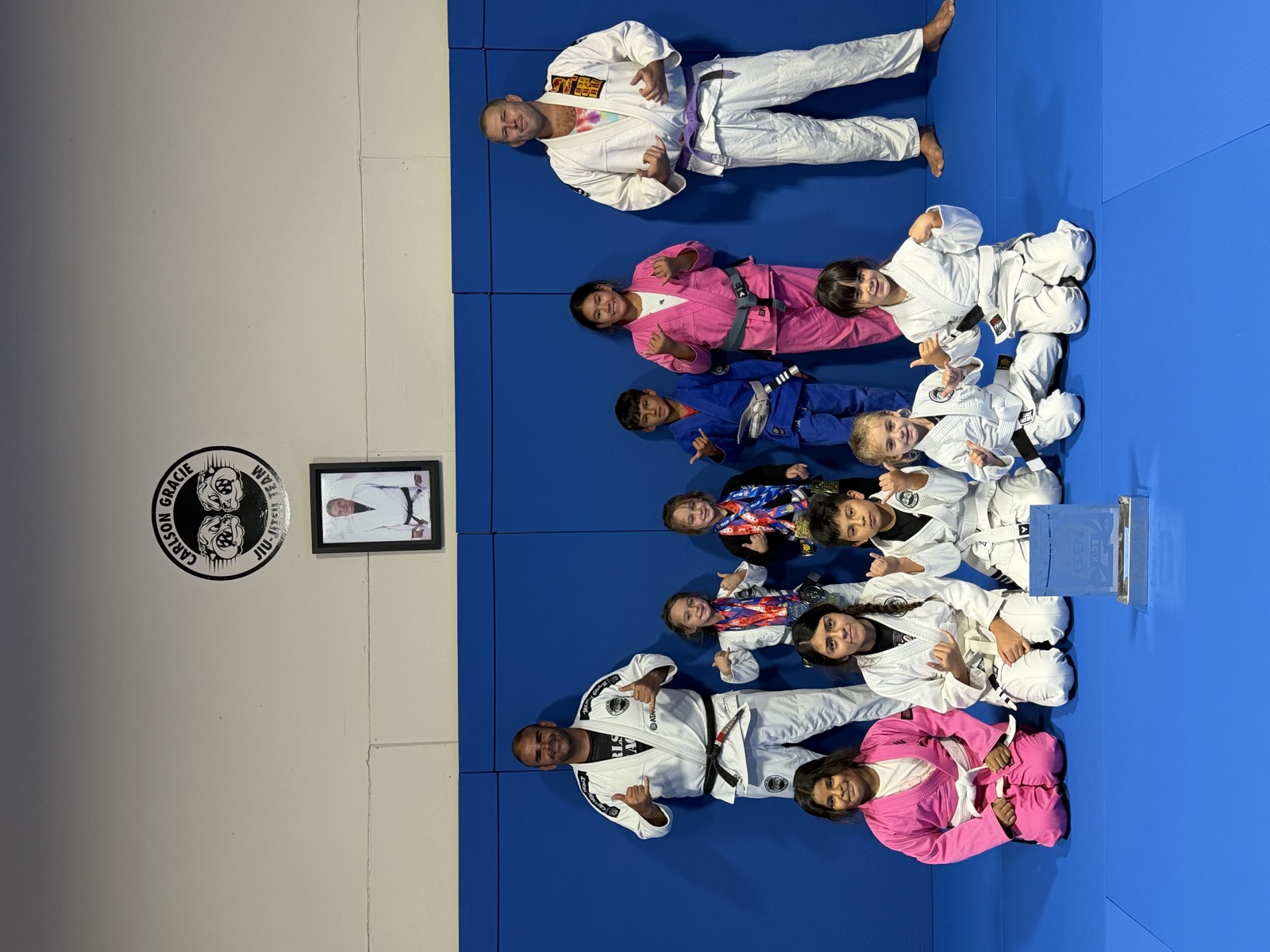 The kids team with their medals and a tournament trophy, with their coaches